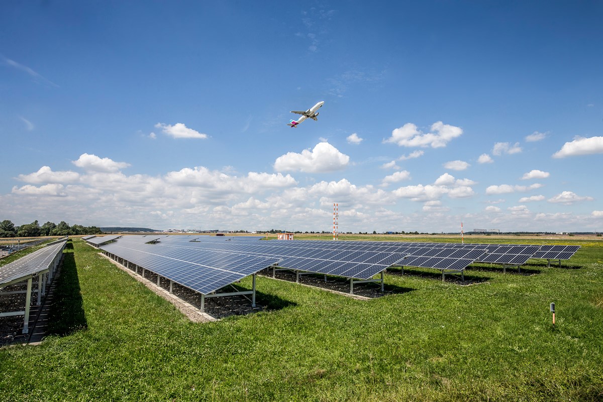 Flugzeug fliegt über Solaranlagen die auf dem Flughafengelände verbaut sind