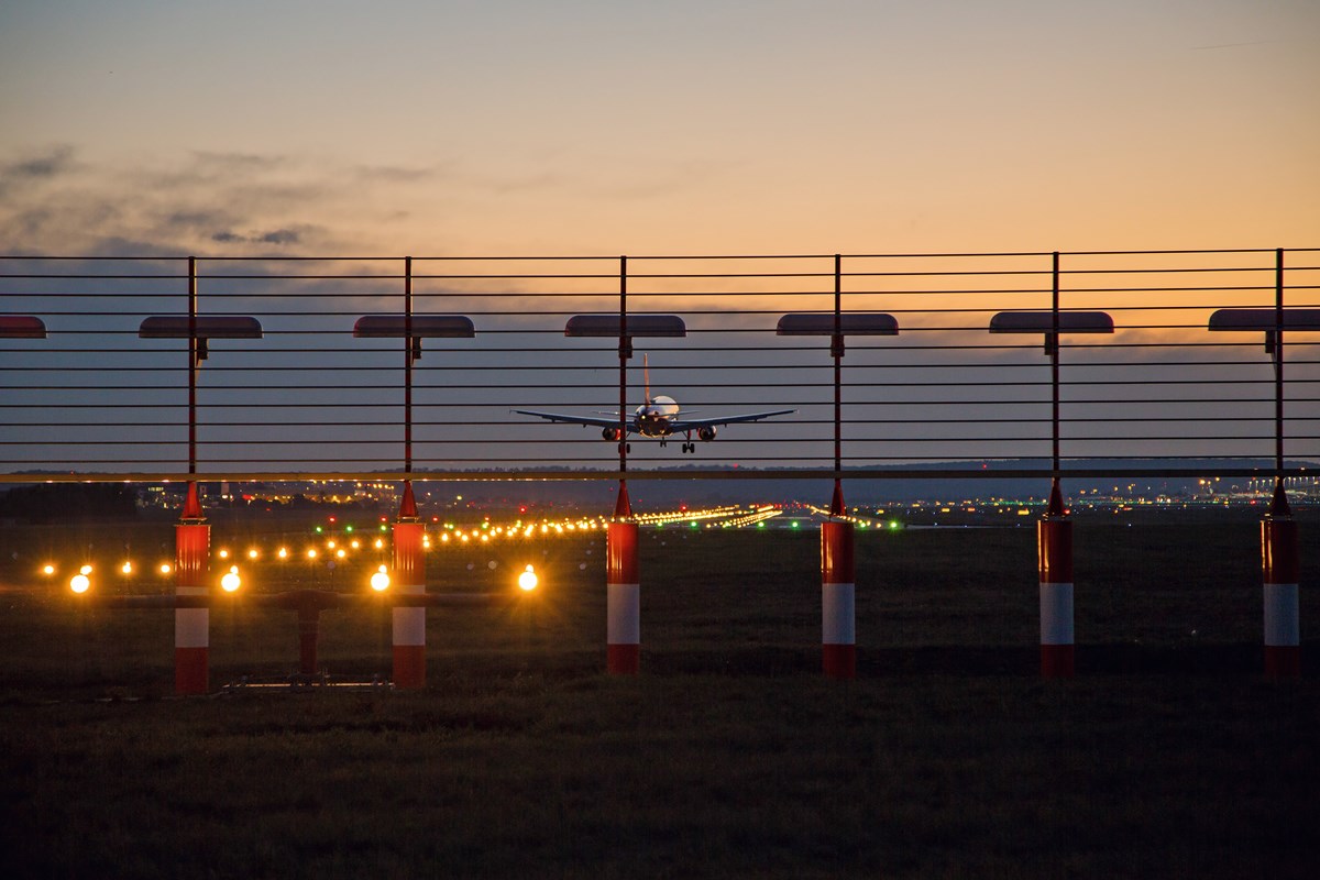 Flugzeug landet in der Abenddämmerung bei eingeschalteter Beleuchtung der Landebahn