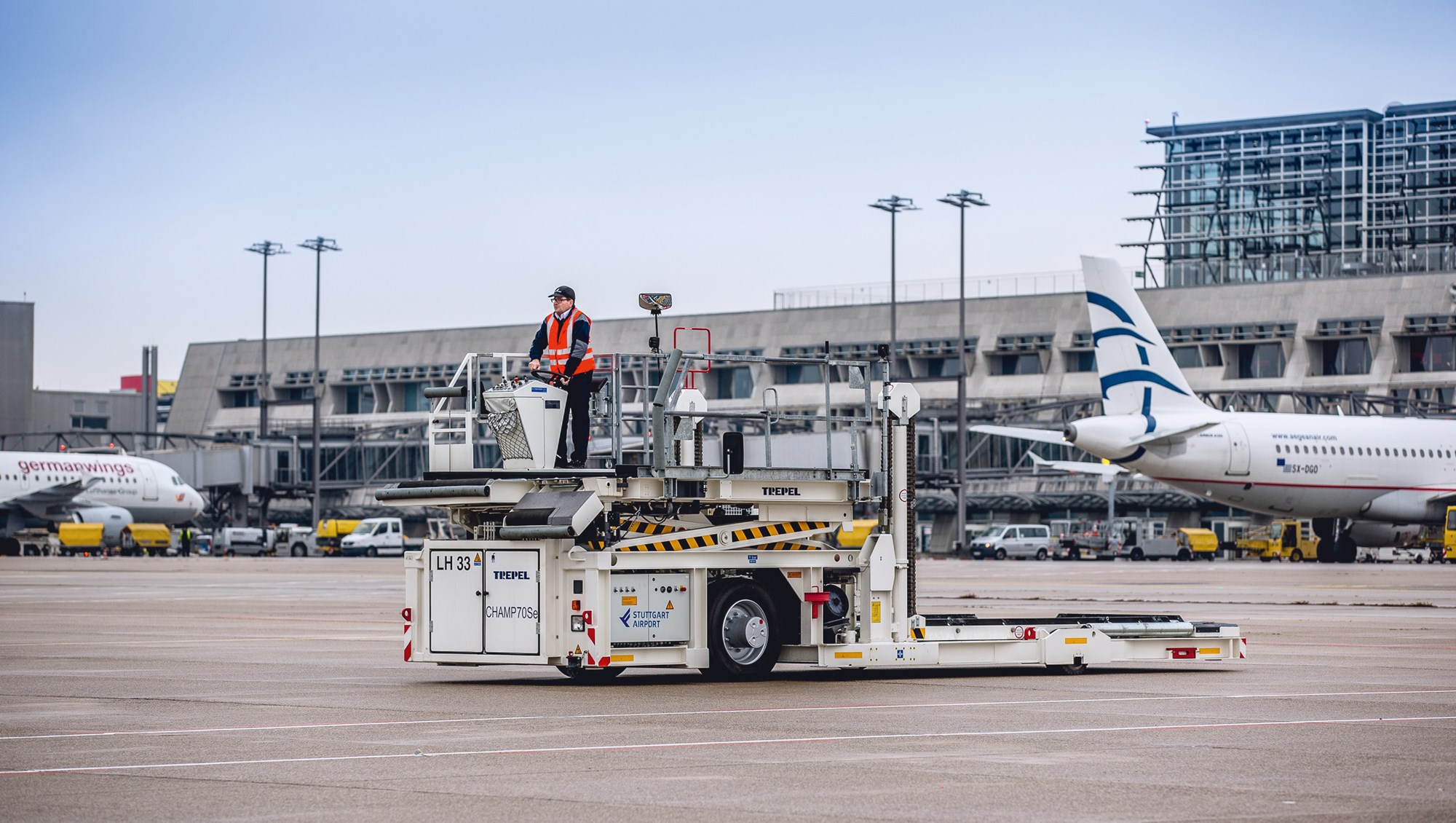 Ein elektrisch betriebener Highloader steht mit seinem Fahrer auf dem Stuttgarter Flughafenvorfeld. 
