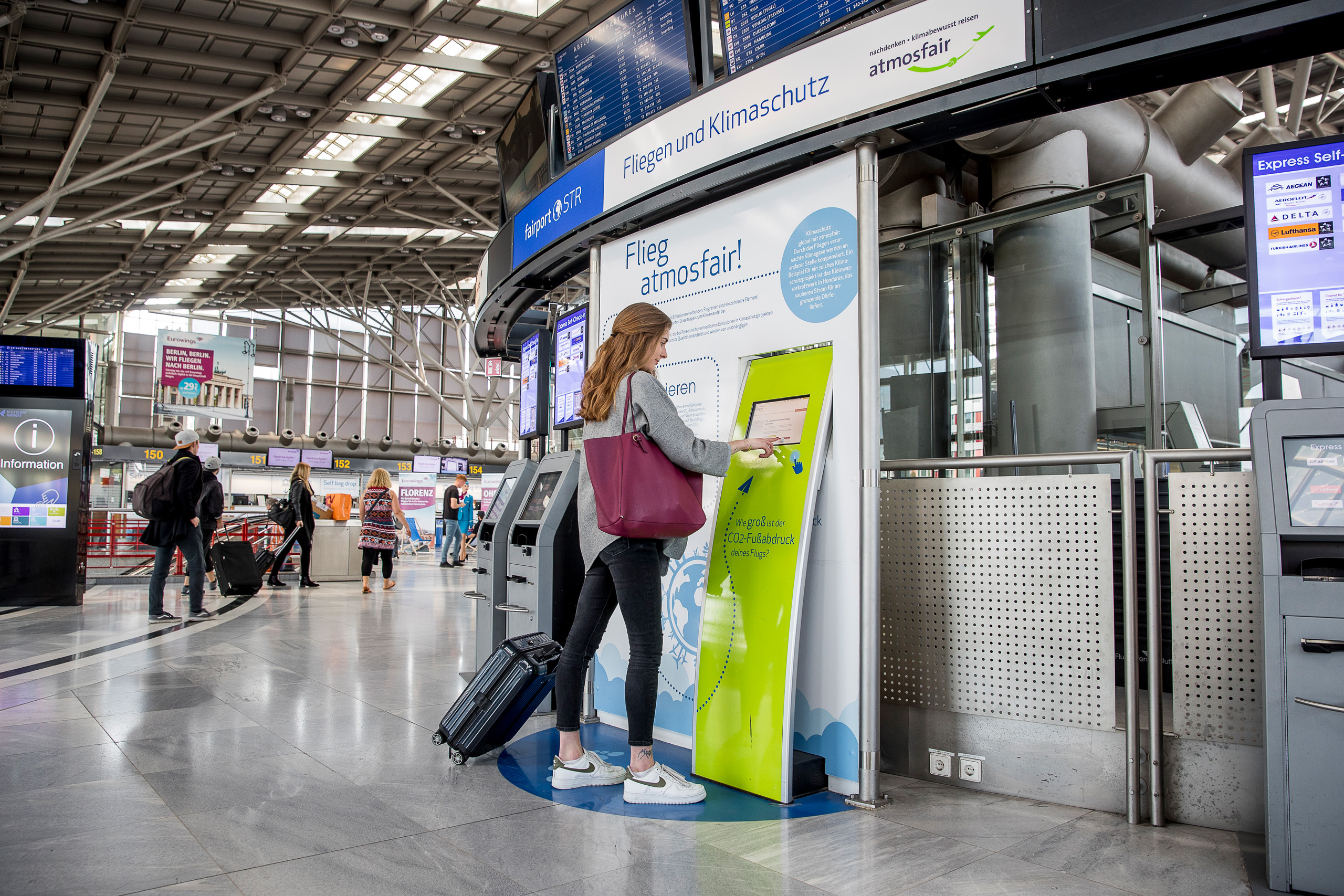 Eine Passagierin berechnet die Emissionen ihres Fluges an der Atmosfair Station im Terminal.
