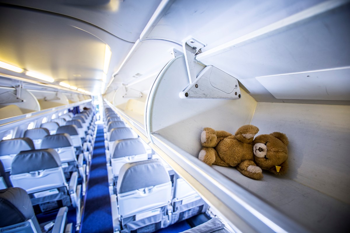 verlorener Teddybär liegt im Gepäckfach eines leeren Flugzeuges 