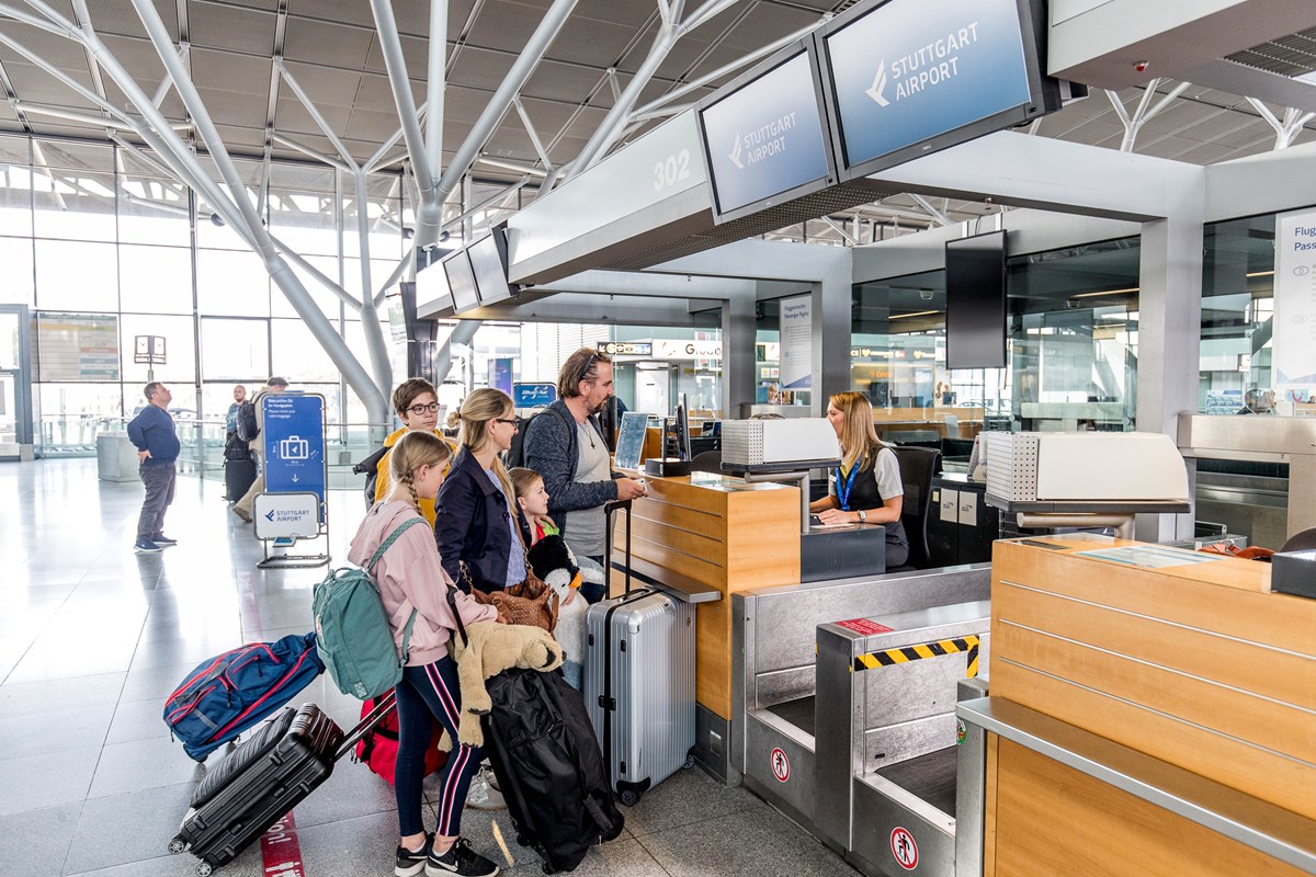 Familie checkt am Flughafen mit ihrem Gepäck am Schalter ein