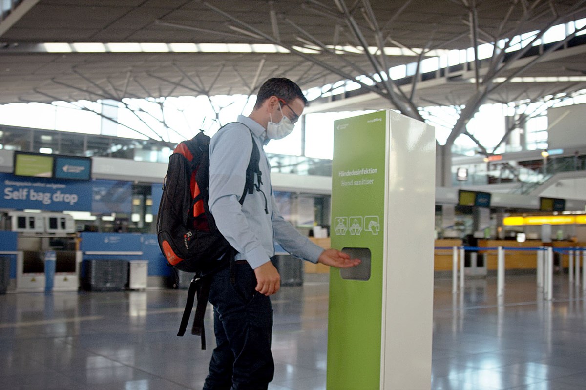 Passagier benutzt Desinfektionsspender im Terminal