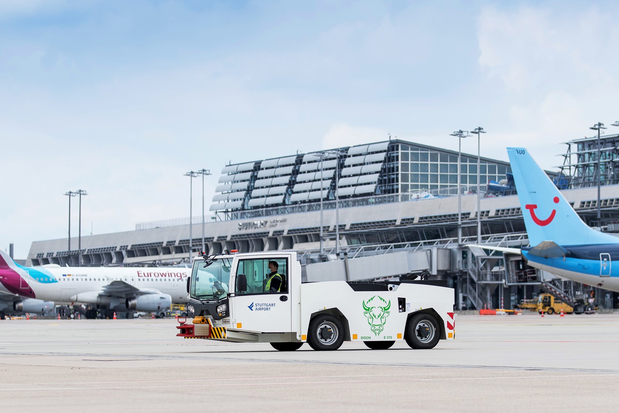 Ein elektrisch betriebenes Pushback-Fahrzeug steht auf dem Stuttgarter Flughafenvorfeld. Im Hintergrund parken Flugzeuge. 