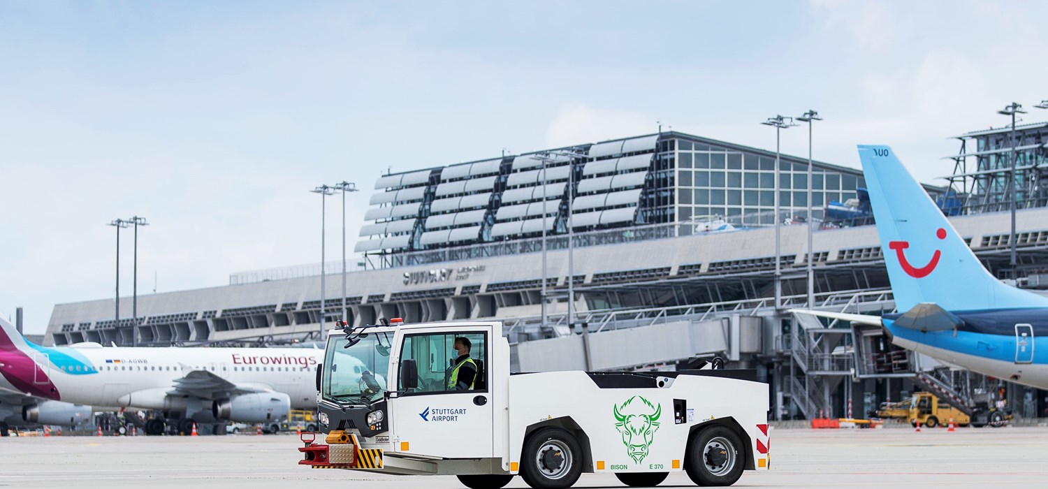 Ein elektrisch betriebenes Pushback-Fahrzeug steht auf dem Stuttgarter Flughafenvorfeld. Im Hintergrund parken Flugzeuge. 