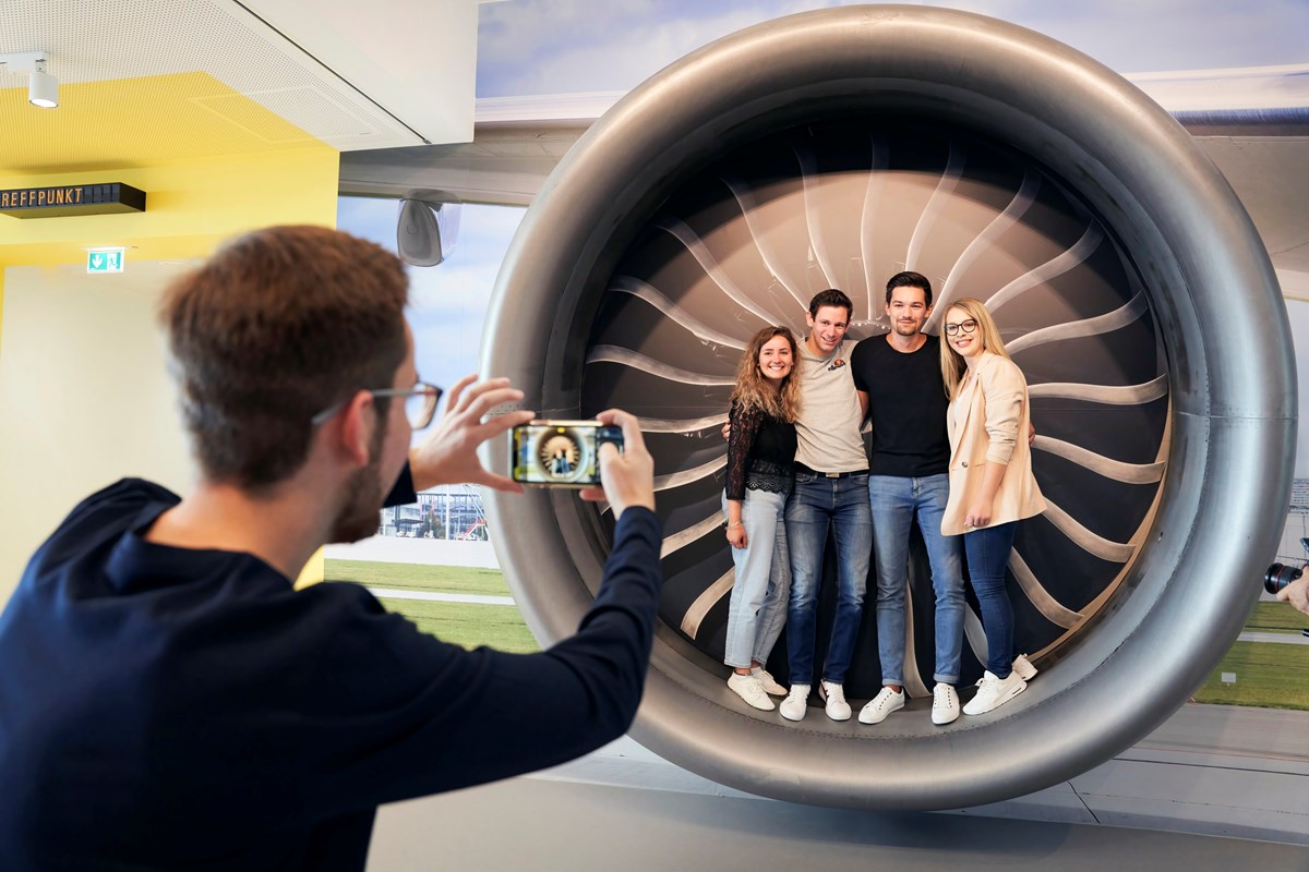 Menschen stehen in Modell einer Flugzeugturbine für Foto ein Erinnerungsfoto an das kostenlose Erlebnis.