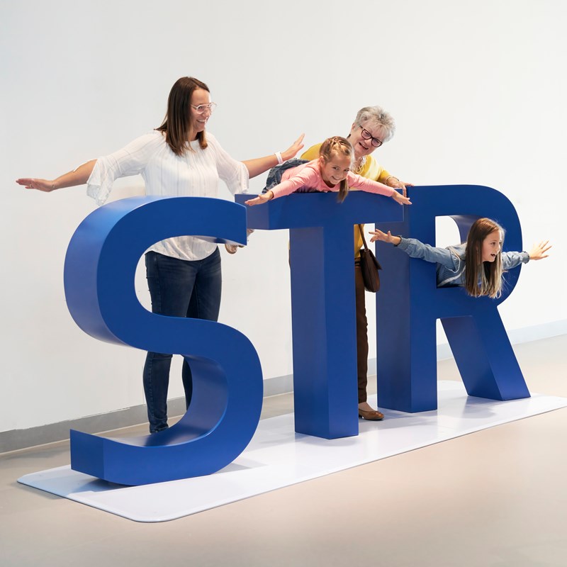 Familie macht gemeinsames Foto an den STR Buchstaben im Besucherzentrum SkyLand