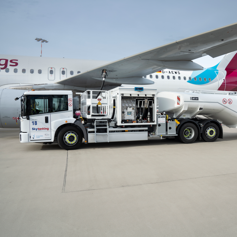 Ein elektrischer Flugzeugtankwagen der Firma Skytanking betankt ein parkendes Flugzeug.